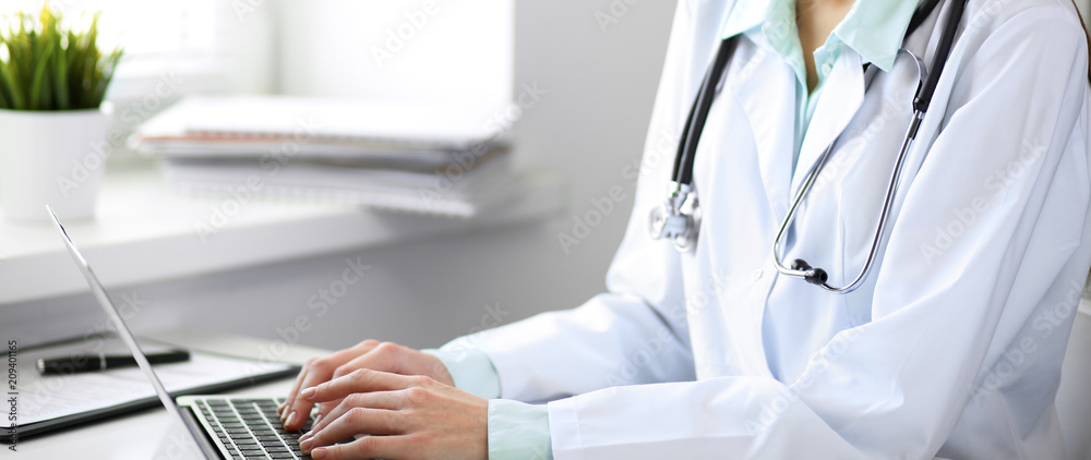 Close up of unknown female doctor sitting at the table near the window in hospital Close up of unknown female doctor sitting at the table near the window in hospital