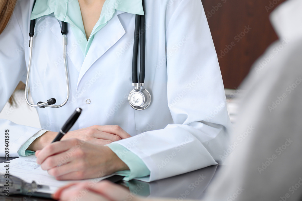 Doctor and patient sitting at the desk near the window in hospital Doctor and patient sitting at the desk near the window in hospital