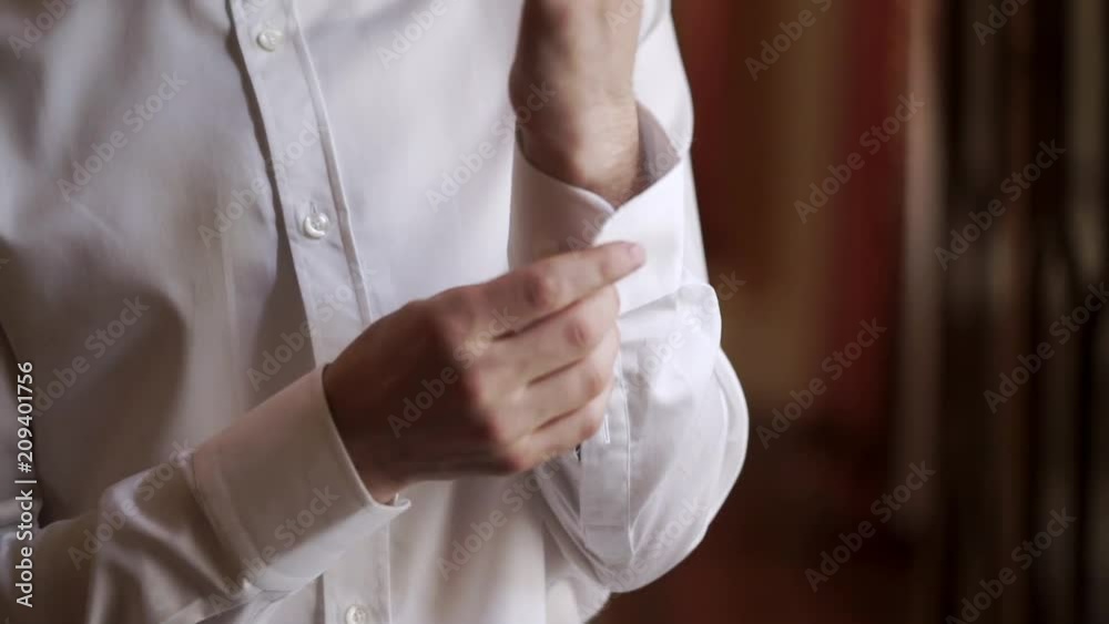 Young man buttoning white shirt closeup Young man buttoning white shirt closeup