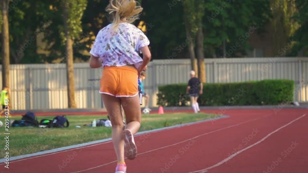 Back view of sporty girl with beautiful legs running sprint on the stadium. Slow motion Back view of sporty girl with beautiful legs running sprint on the stadium. Slow motion