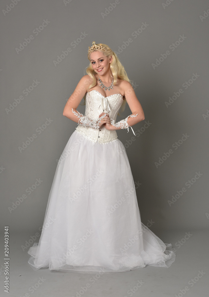 full length portrait of blonde girl wearing white corset gown. standing pose on grey studio background. full length portrait of blonde girl wearing white corset gown. standing pose on grey studio background.
