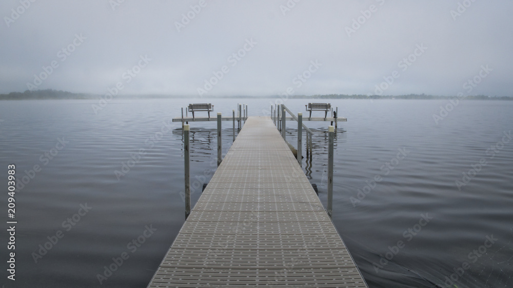Fototapeta premium Dok z ławkami na mglistym jeziorze w Bemidji Minnesota