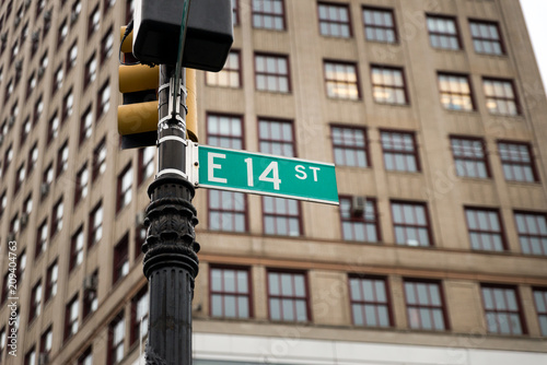 New York City East 14th Street (Fourteenth Street) sign with buildings in th ebackground showing symmetry and city vibes  photo