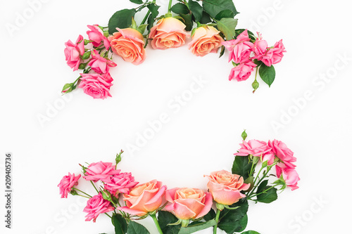 Floral frame made of rink and orange roses, buds and green leaves on white background. Flat lay, top view. Spring background