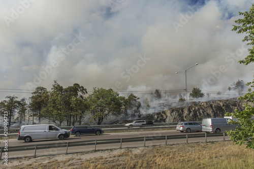 Dramatisk skogsbrand rasar vid Värmdöleden i Nacka fredag 15/6 och bilarna kör genom röken nära elden photo