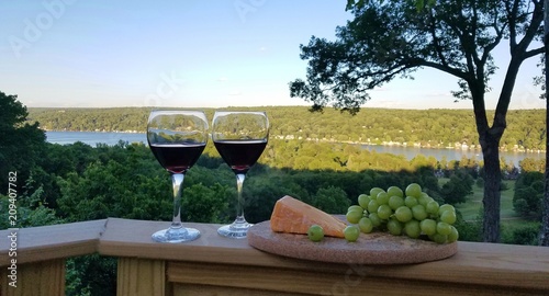 Red Wine in Glasses with Cheese and Grapes Against a Rustic Water View Nearing Dusk; Wines, Wine Tasting,  Life of Leisure, Relaxing Ideas photo