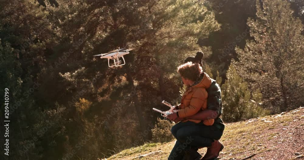 Hipster father and young son flying drone together in nature