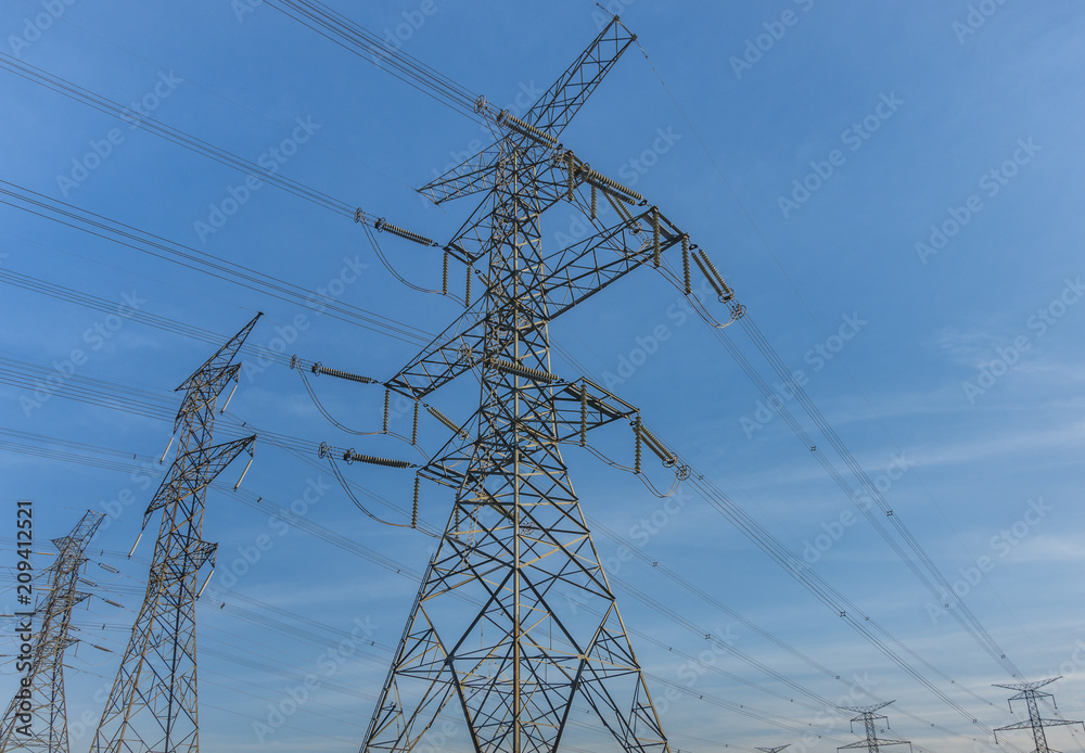 Electric poles and power lines in a North American suburban area on a blue sky background Electric poles and power lines in a North American suburban area on a blue sky background