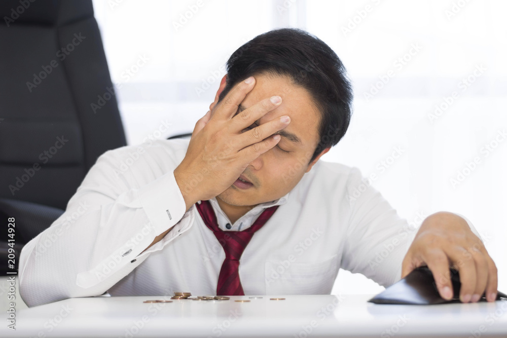 A bankrupt, broke and frustrated man is having financial problems with coins left on the table and an empty wallet. A bankrupt, broke and frustrated man is having financial problems with coins left on the table and an empty wallet.