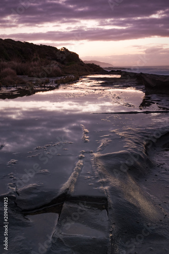 Sunrise reflecting in a pool of water at an Australian beach alongside the iconic Great Ocean Road