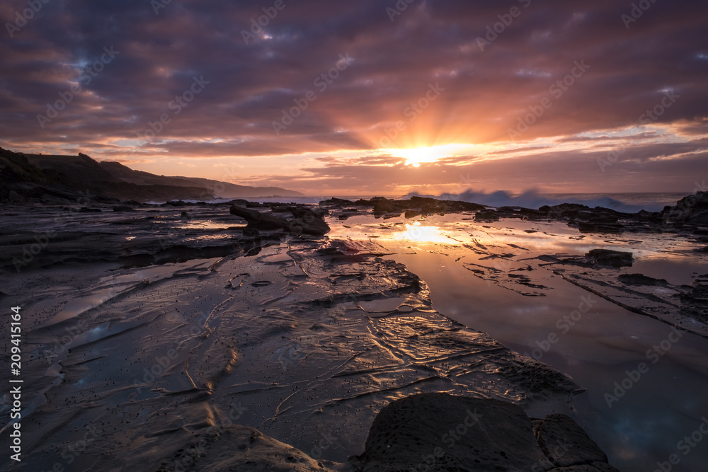 Sunrise reflecting in a pool of water at an Australian beach alongside the iconic Great Ocean Road