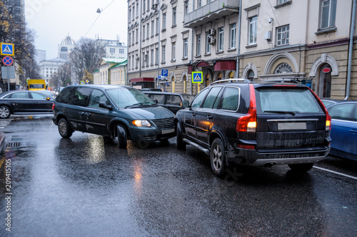 A car accident in the city in rainy weather between a minivan and an SUV. General form.