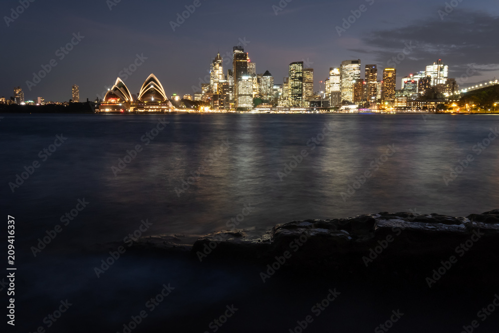 Sydney city lit up in the evening and spilling light over the beautiful Sydney Harbour