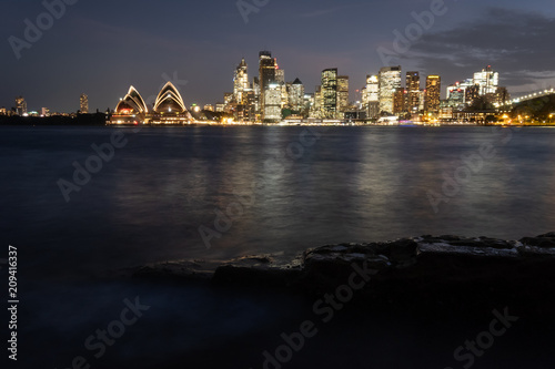 Sydney city lit up in the evening and spilling light over the beautiful Sydney Harbour