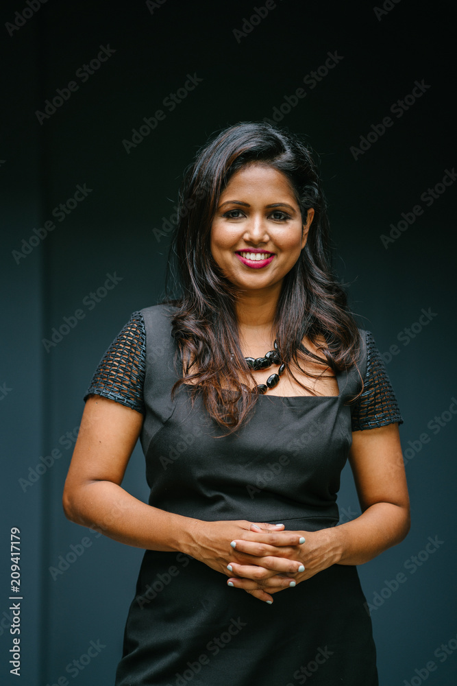 A portrait of a confident Indian woman in a studio. She is dressed