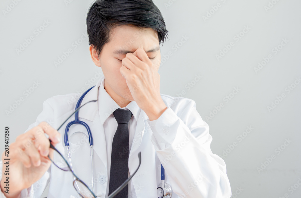 Stressed . Asian of homosexuality Doctor in sitting at his desk with Headphones in his office at the hospital Stressed . Asian of homosexuality Doctor in sitting at his desk with Headphones in his office at the hospital