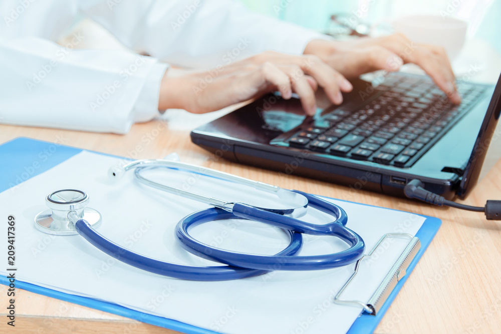 Stethoscope on desk with doctor using digital technology laptop computer medical working at office. Stethoscope on desk with doctor using digital technology laptop computer medical working at office.