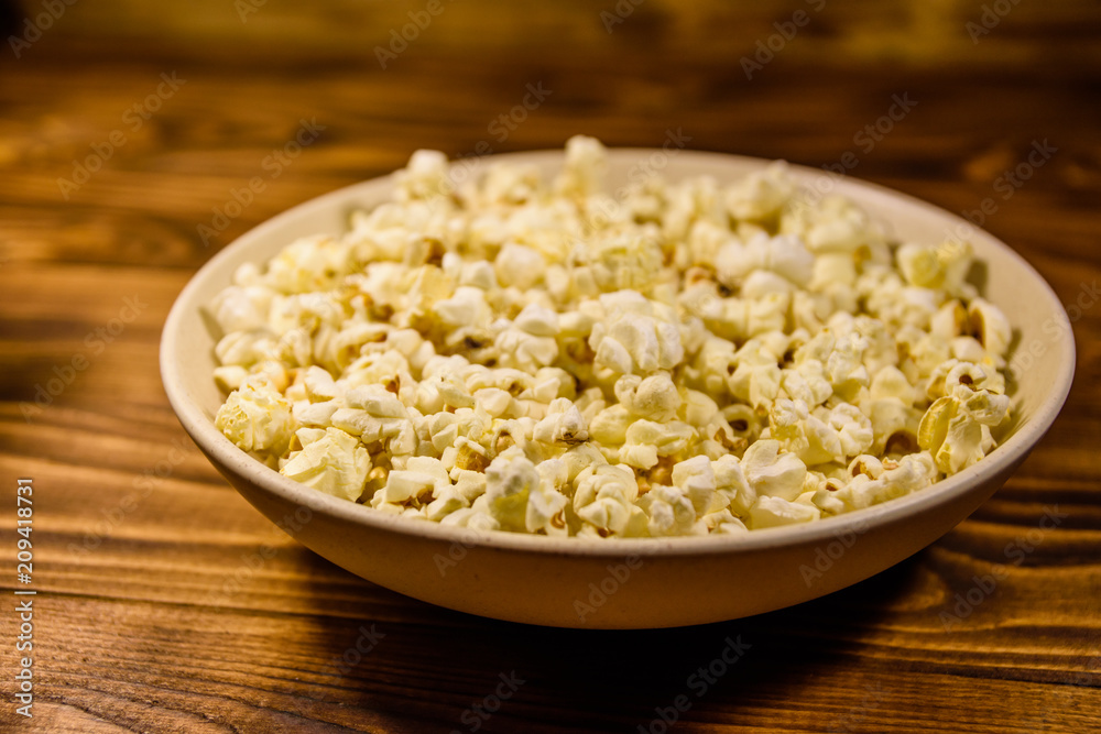 Ceramic plate with popcorn on wooden table Ceramic plate with popcorn on wooden table