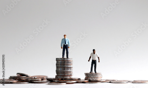 Racial wage gap concept. Miniature people standing on a pile of coins. photo