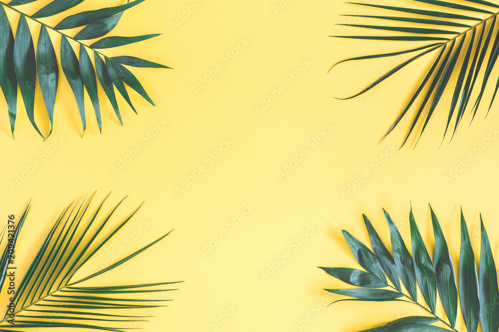 Tropical palm leaves on yellow background. Summer concept. Flat lay, top view, copy space Tropical palm leaves on yellow background. Summer concept. Flat lay, top view, copy space