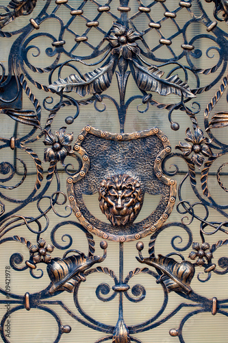 Details, structure and ornaments of forged iron gate. Decorative ornamen with lions , made from metal