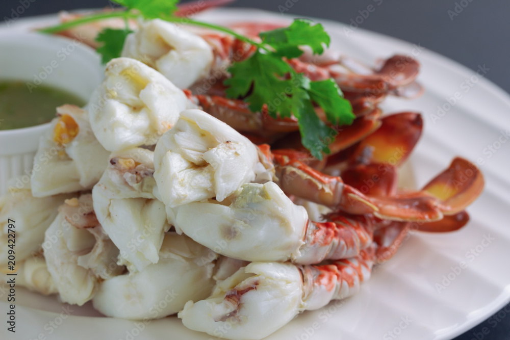 Steamed crab meat prepared for ready to eat with Thai style hot and spicy dipping sauce on white plate put on black granite table in close up view macro style. Delicious homemade seafood concept. Steamed crab meat prepared for ready to eat with Thai style hot and spicy dipping sauce on white plate put on black granite table in close up view macro style. Delicious homemade seafood concept.