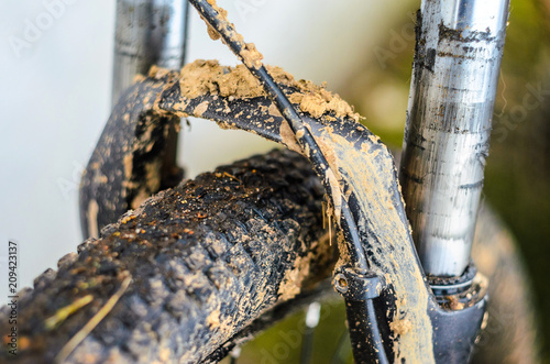 Dirty Mountain Bike Suspension Fork After Riding in Bad Weather. Dirt and Oil Stains on the Legs of the Mountain Bike Fork photo