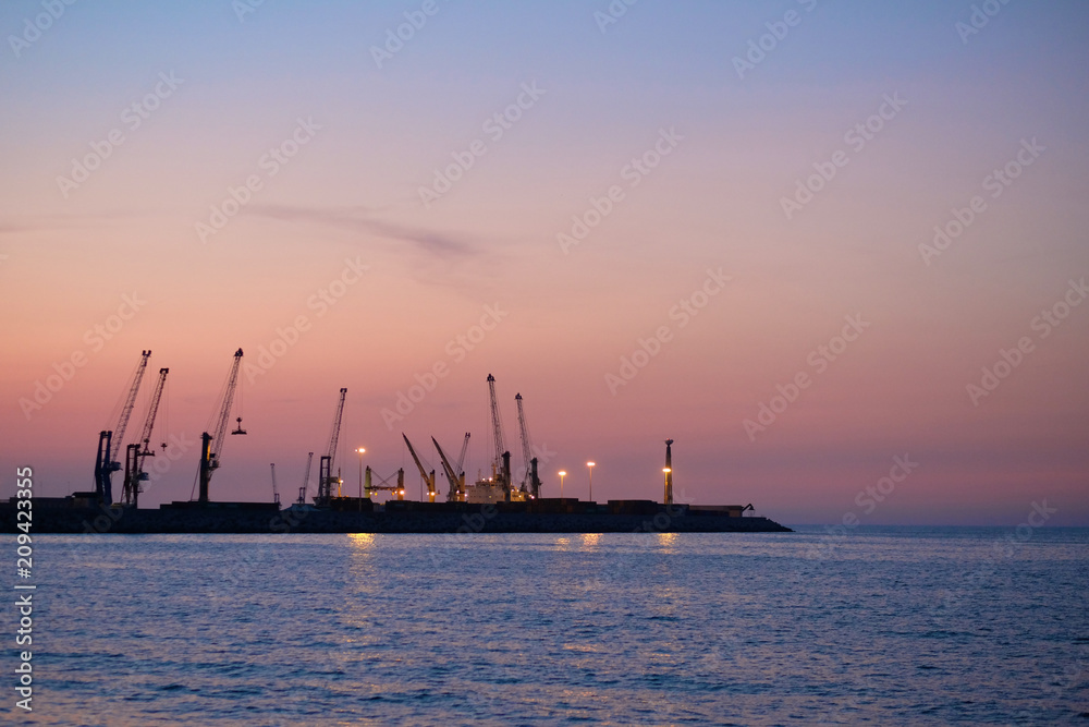 Panorama of the sea cargo port against the backdrop of the setting sun