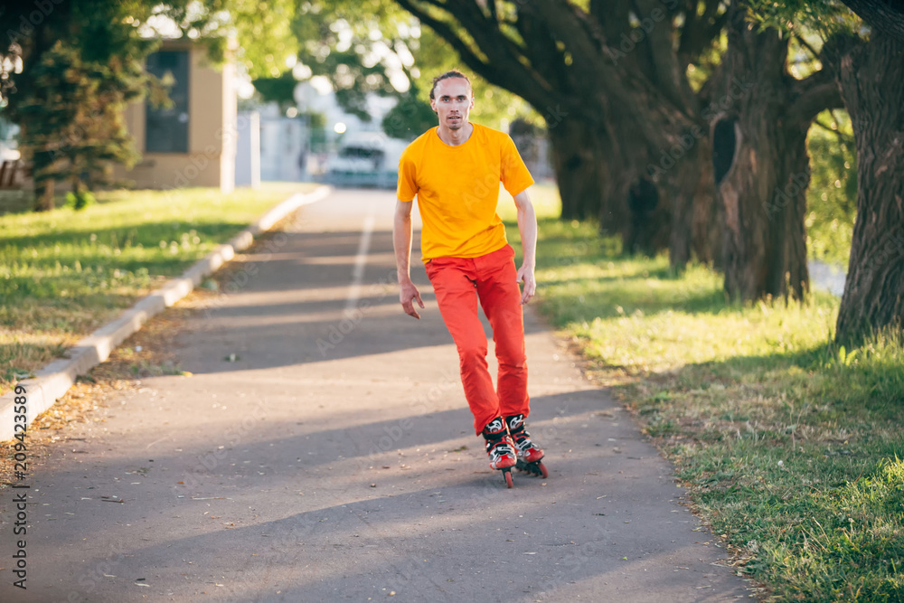 the guy goes on roller Skates. playing sports. in the orange bright. On the Sunset. recreation. the guy goes on roller Skates. playing sports. in the orange bright. On the Sunset. recreation.