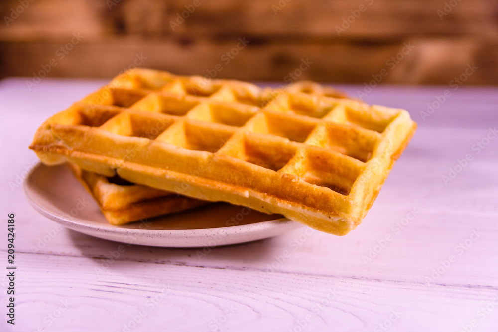 Ceramic plate with belgian waffles on wooden table