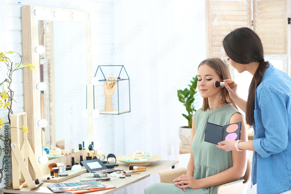 Obraz premium Professional visage artist applying makeup on woman's face in salon