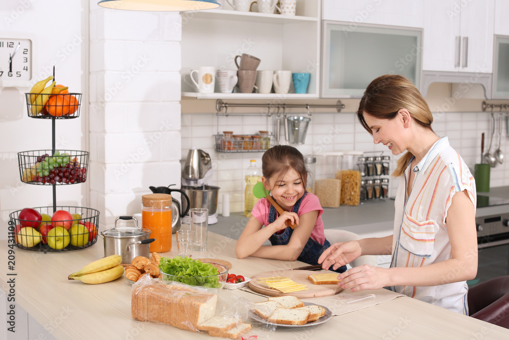 Housewife with her daughter preparing dinner on kitchen Housewife with her daughter preparing dinner on kitchen