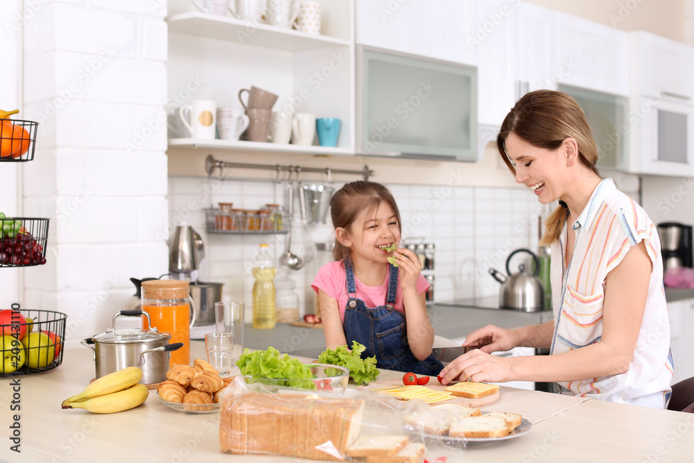 Housewife with her daughter preparing dinner on kitchen