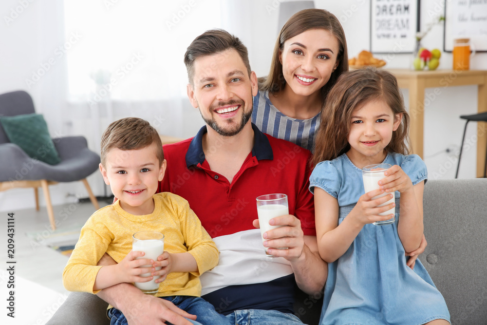 Obraz premium Happy family with glasses of milk in living room