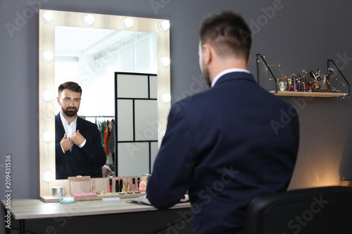 Photos Young handsome man near mirror in makeup room