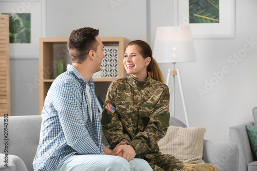 Tableau sur toile Woman in military uniform with her husband on sofa at home