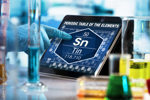 Scientist working on the digital tablet data of the chemical element Tin Sn / researcher consulting information on the computer of the periodic table of elements 