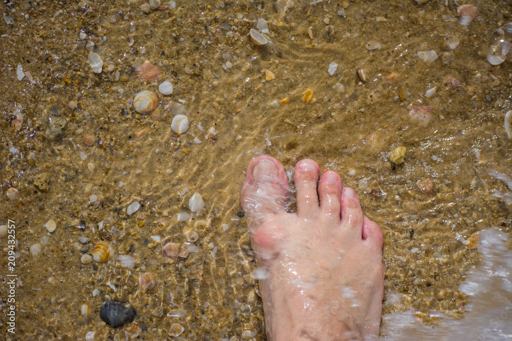Man walking bare foot on sandy beach into ocean wave, point of view. Man walking bare foot on sandy beach into ocean wave, point of view.
