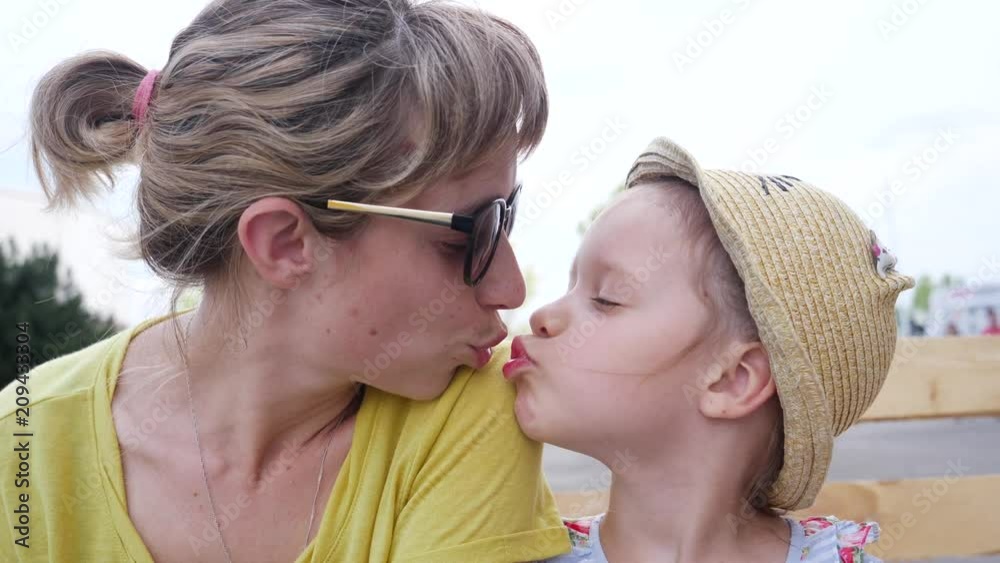 Young mother and child girl daughter tenderly kiss each other ... 