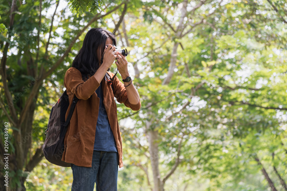Asian male traveler carried a travel bag on back and take a photo by camera in the forest. concept of travel, trip Asian male traveler carried a travel bag on back and take a photo by camera in the forest. concept of travel, trip