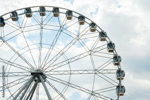 White fluffy clouds in deep blue sky  big Ferris wheel on sky background