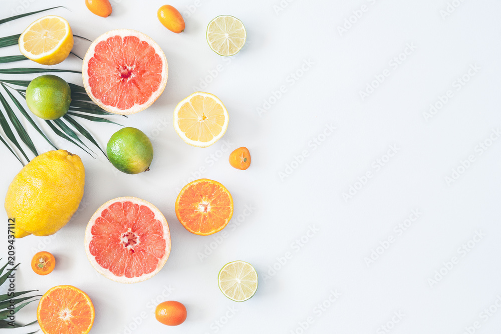 Fruit background. Colorful fresh fruits and tropical palm leaves on pastel blue background. Summer concept. Flat lay, top view, copy space