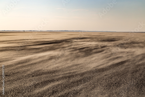 Strand von Spiekeroog bei Starkwind im Winter mit einsamer Person am Horizont