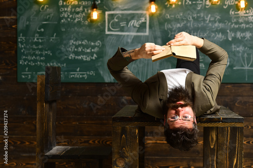 Businessman in suit read on school desk. Bearded man read book in classroom. Scientist hipster with book on table. Teacher with long beard on genius face. Literature lesson at library and bibliopole