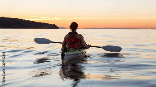 Cinemagraph of a woman enjoying the beautiful ocean scenery on a sea kayak during a vibrant sunset. Taken near Jericho Beach, Vancouver, British Columbia, Canada. Still image continuous loop animation