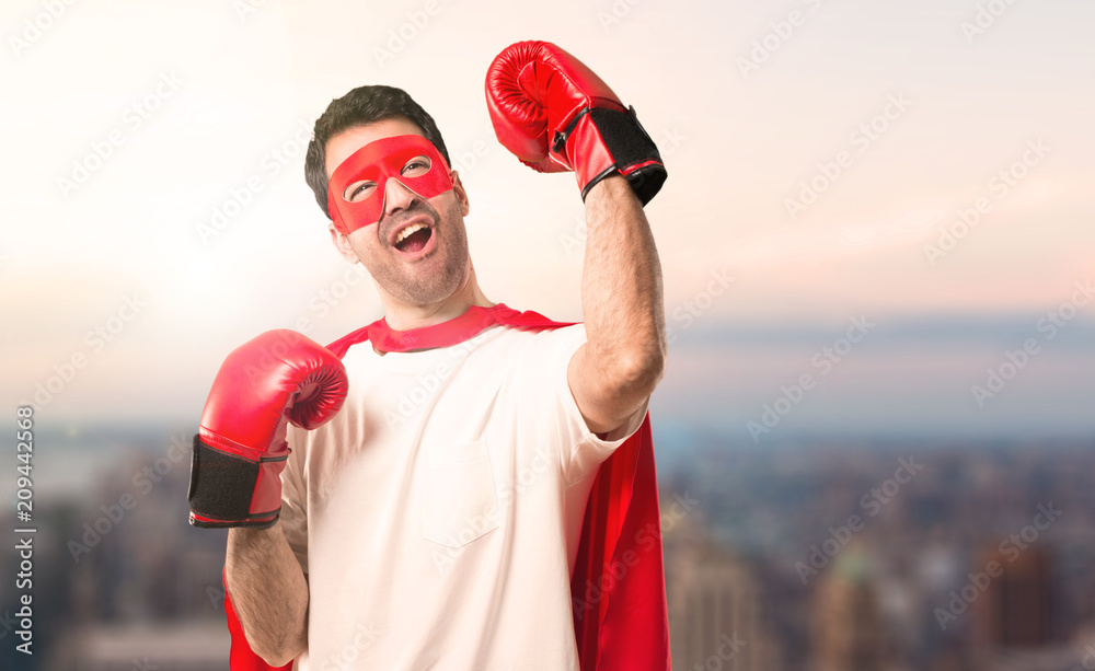 Superhero man with mask and red cape and with boxing gloves on a sunset background Superhero man with mask and red cape and with boxing gloves on a sunset background