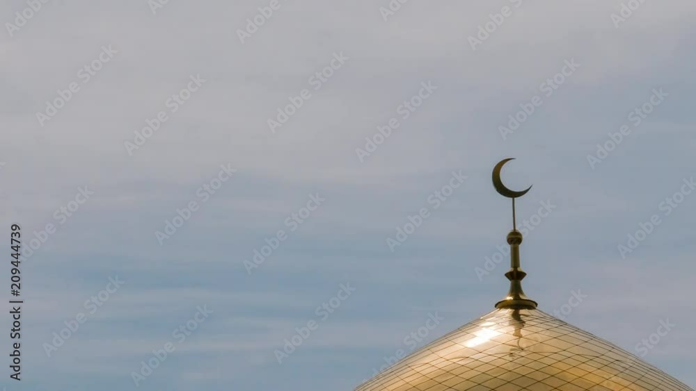TimeLapse. The golden crescent on the minaret of the Islamic mosque on a heavenly blue background with white clouds. TimeLapse. The golden crescent on the minaret of the Islamic mosque on a heavenly blue background with white clouds.