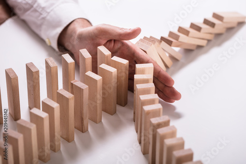 Businessperson Stopping Wooden Blocks From Falling photo