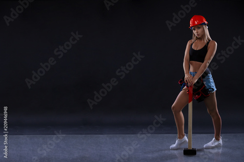 Young beautiful woman with hammer. Strong muscular sporty girl ready for active exercise in sport gym. Strength and motivation concept.