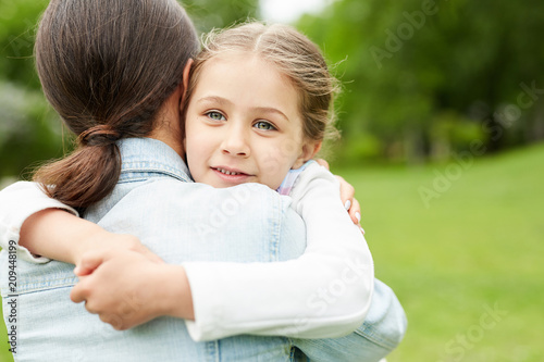 Cute girl embracing her mother while spending time with her in park